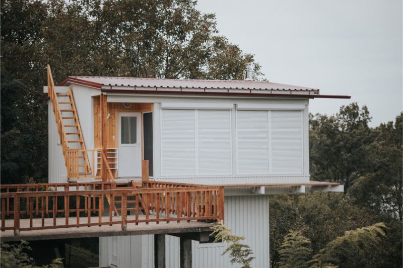 une maison blanche avec un toit rouge et une échelle